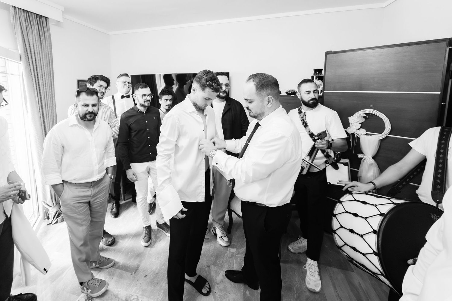 Black and white photo of wedding party guests mingling and socializing at indoor reception.