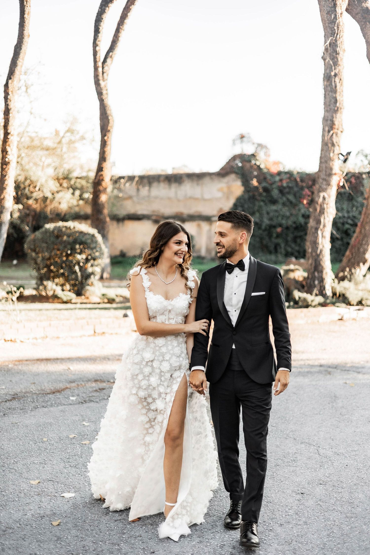 Candid walking shots of couple celebrating along a tree-lined path at sunset.