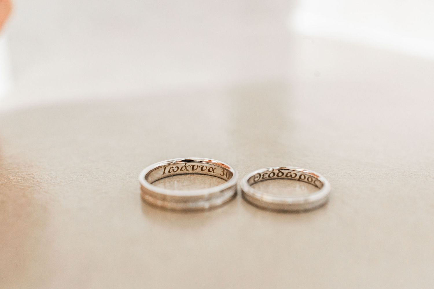 Close-up shot of elegant wedding rings on a light beige surface.