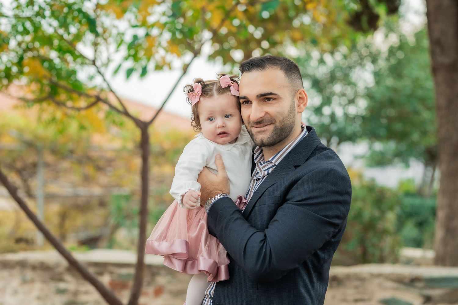 A happy family enjoys a tender moment together outdoors during an autumn photoshoot in a park setting.