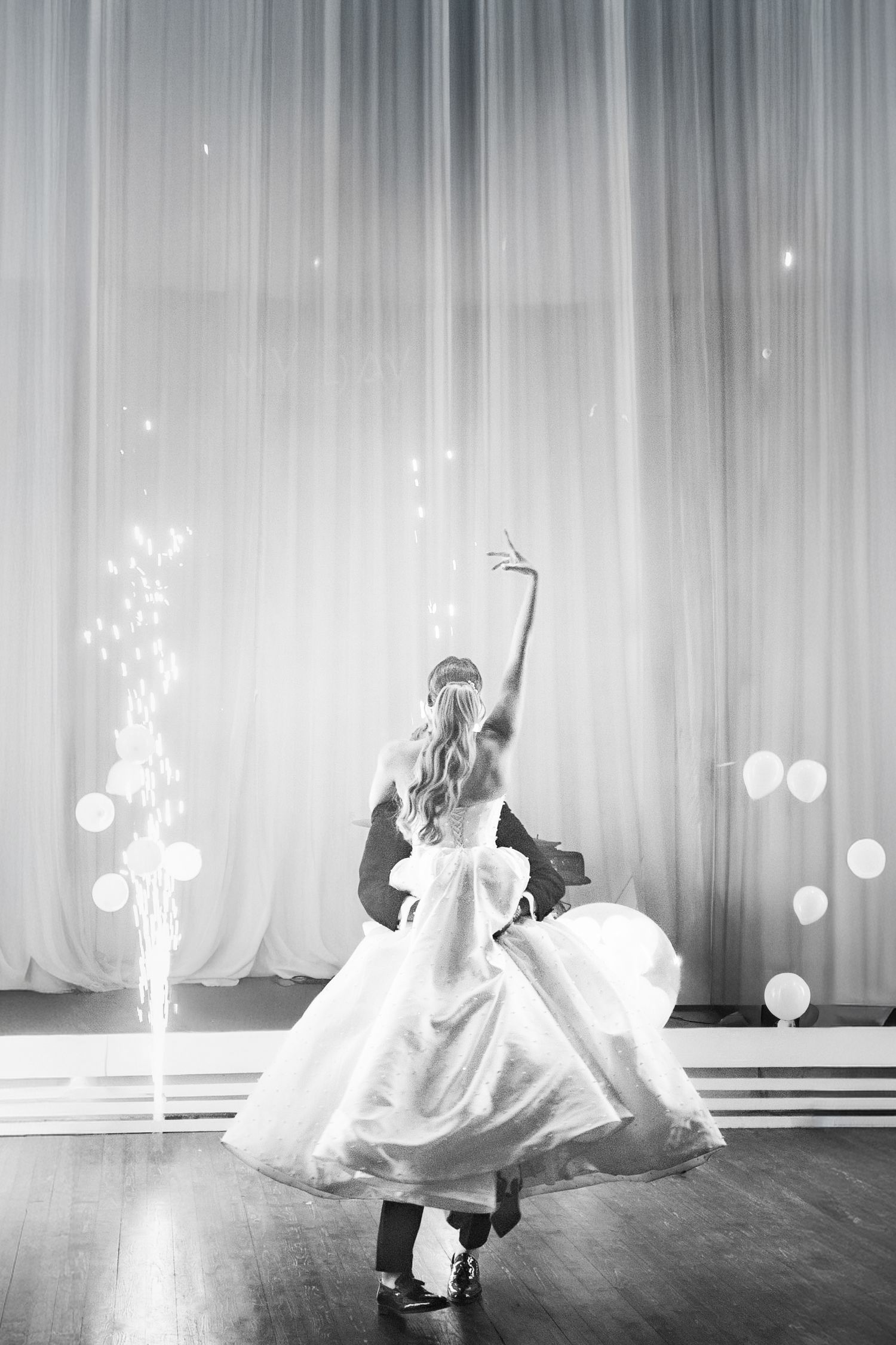 Black and white artistic wedding dance photo with dramatic movement and lighting.