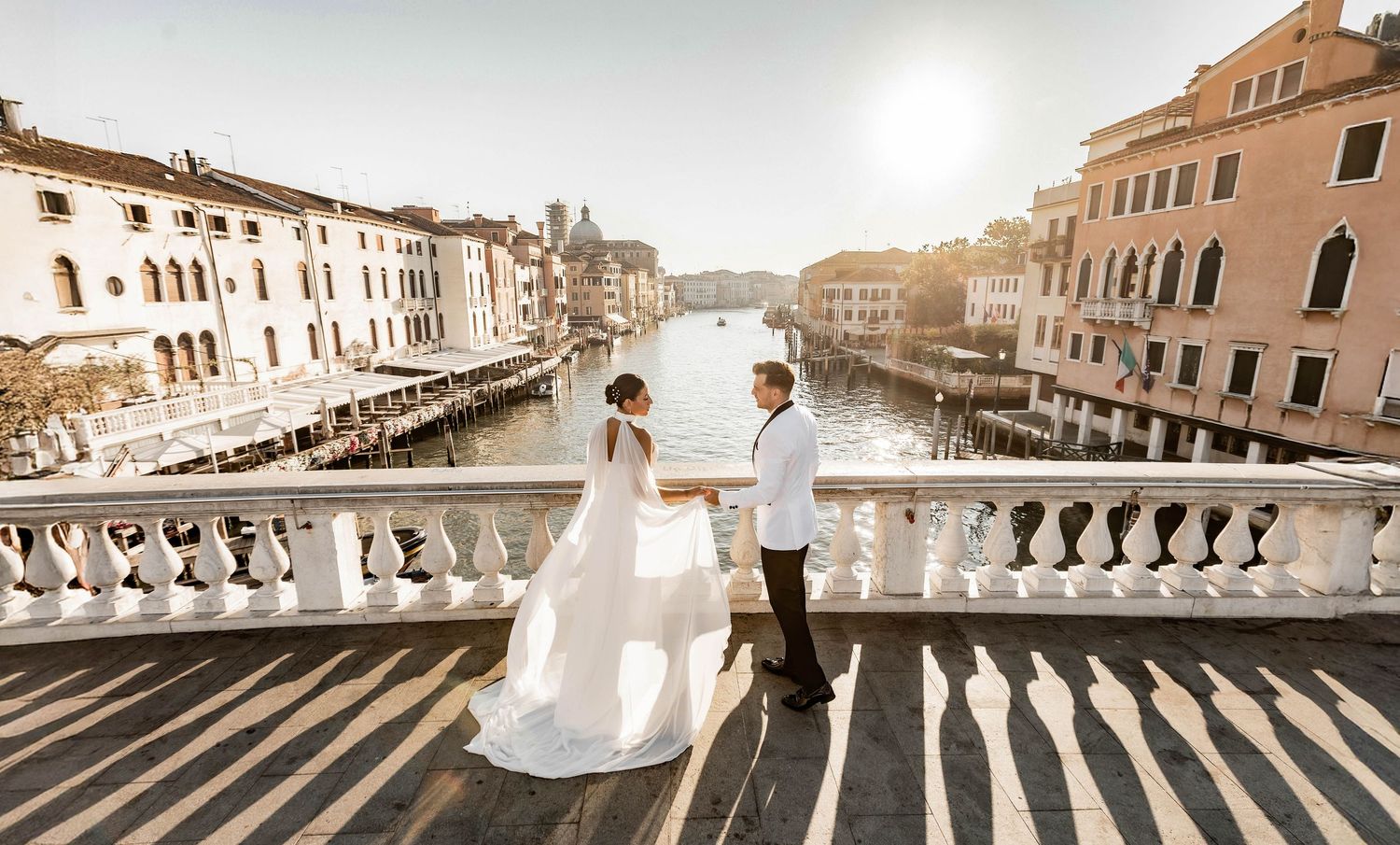 Panoramic view of Venice's historic buildings and canals in warm sunlight.
