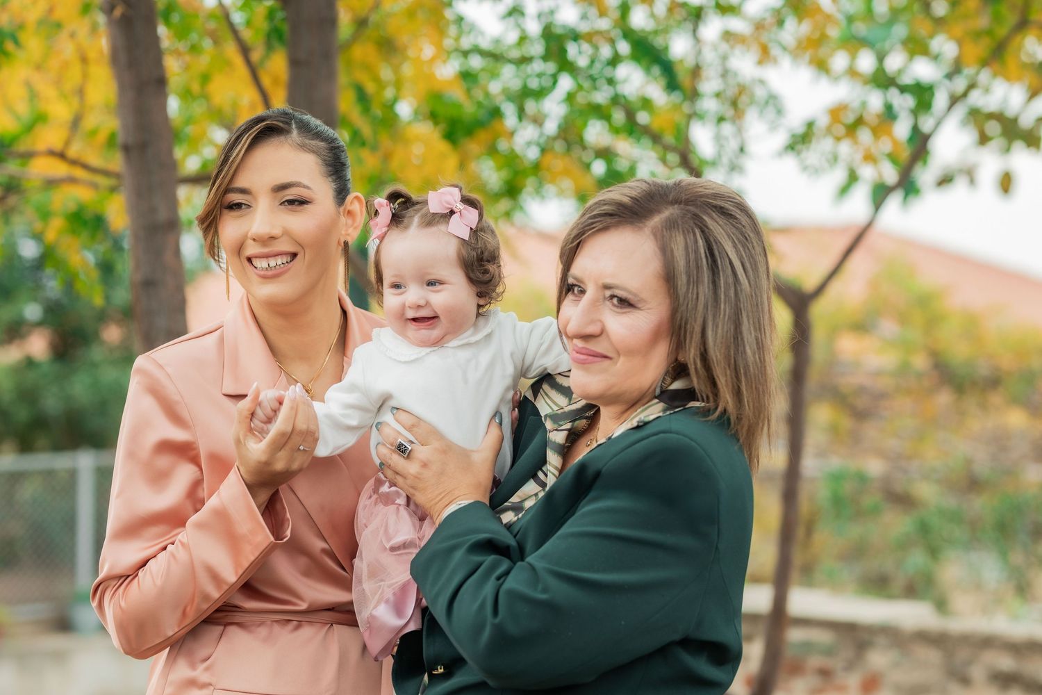 Three people enjoying a sunny autumn day outdoors with golden foliage in the background.