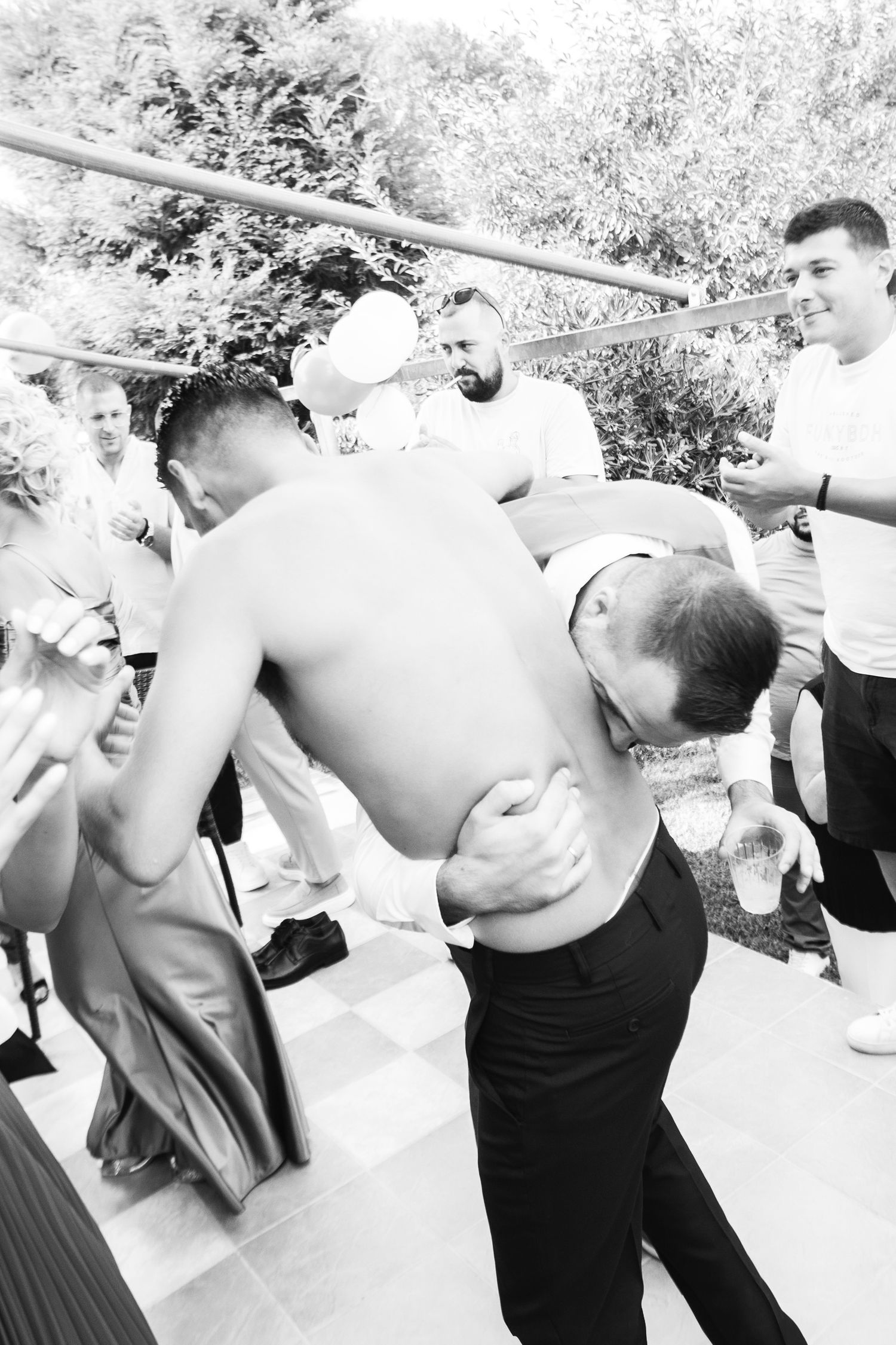 Wedding guests dance energetically in black and white photography.