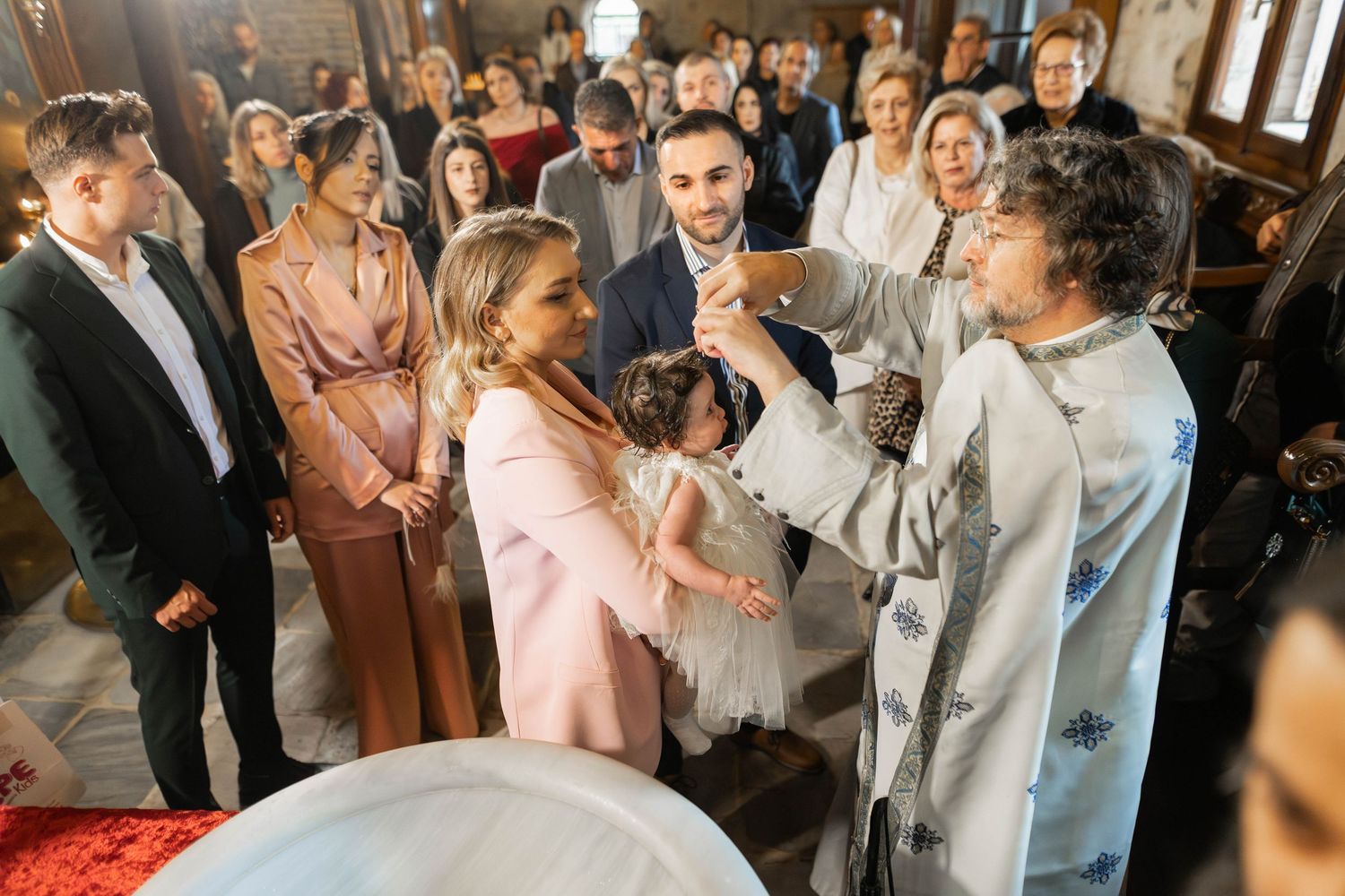 Wedding guests mingle and dance together during a lively reception celebration at an indoor venue.