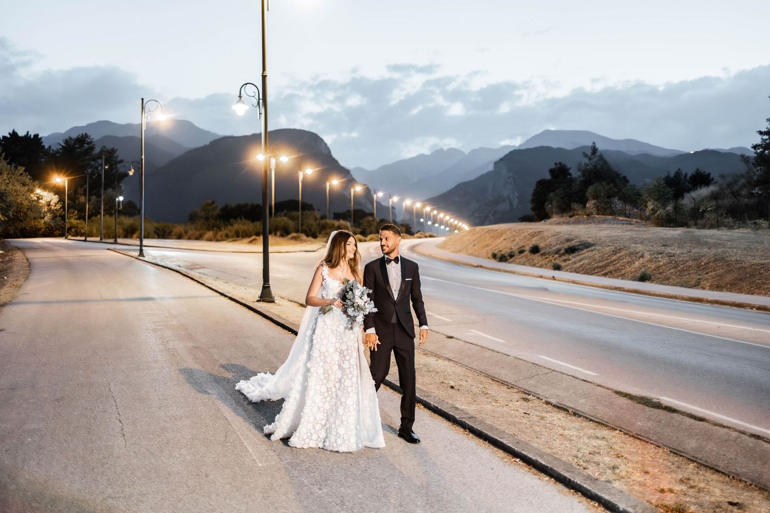 Romantic sunset wedding photos captured along a mountain road with street lights.