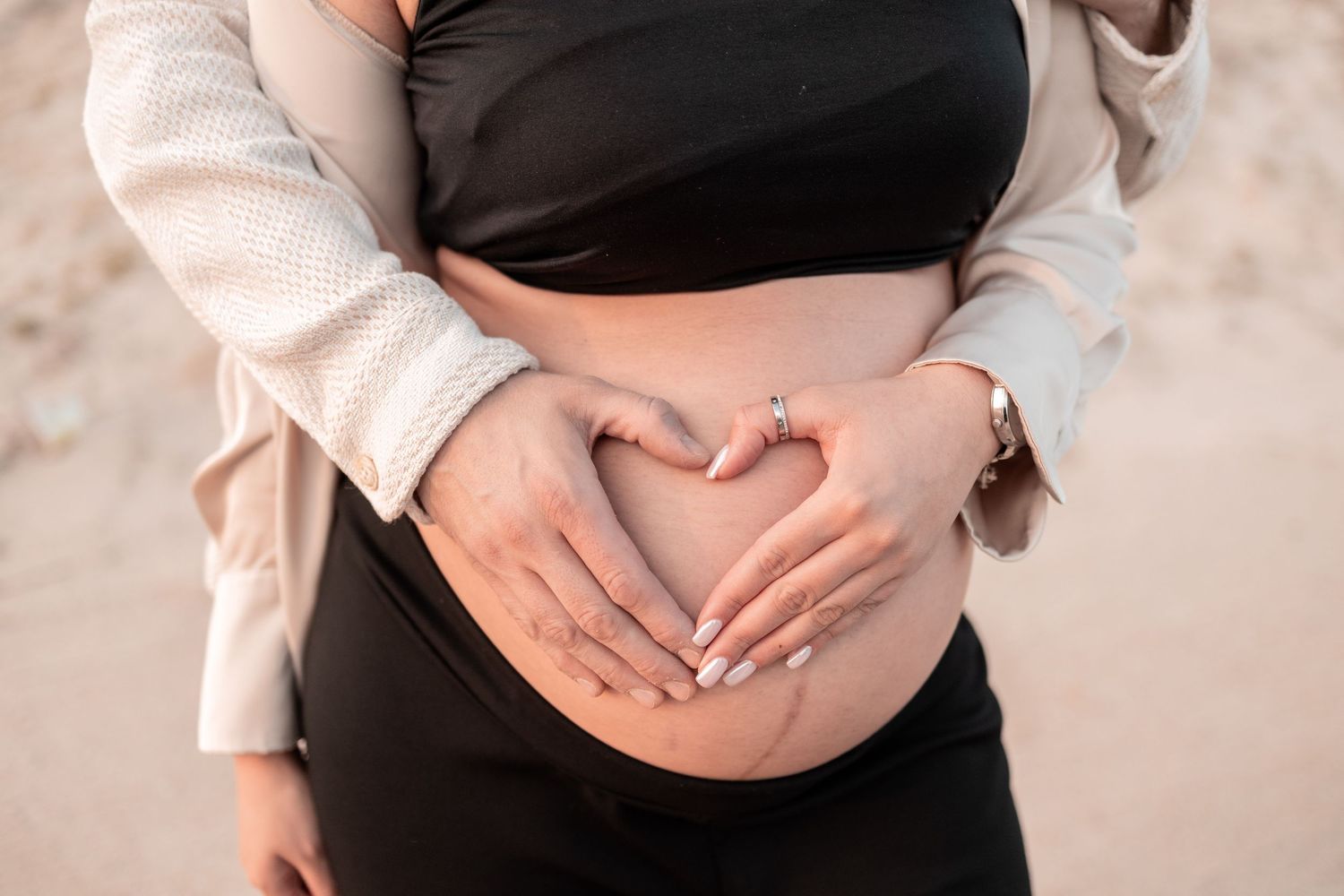 A series of maternity photos showing hands forming a heart shape over a pregnant belly.