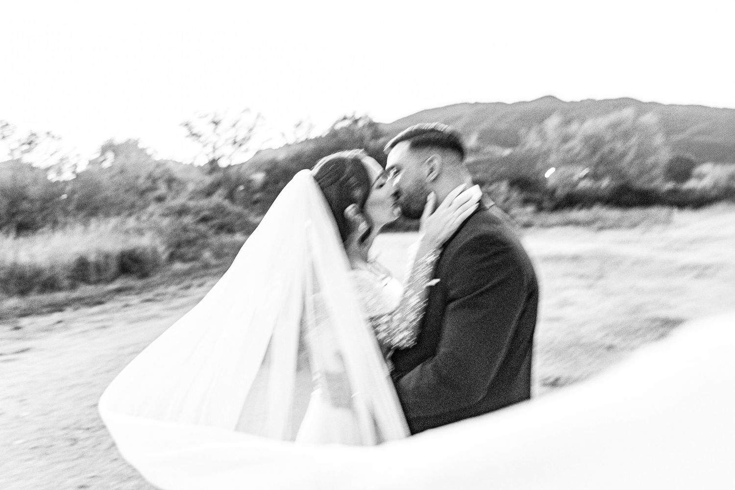 Black and white romantic wedding portrait with mountains in background.