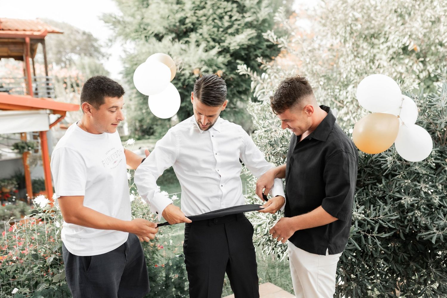 Wedding party members celebrate with balloons in an outdoor garden setting.