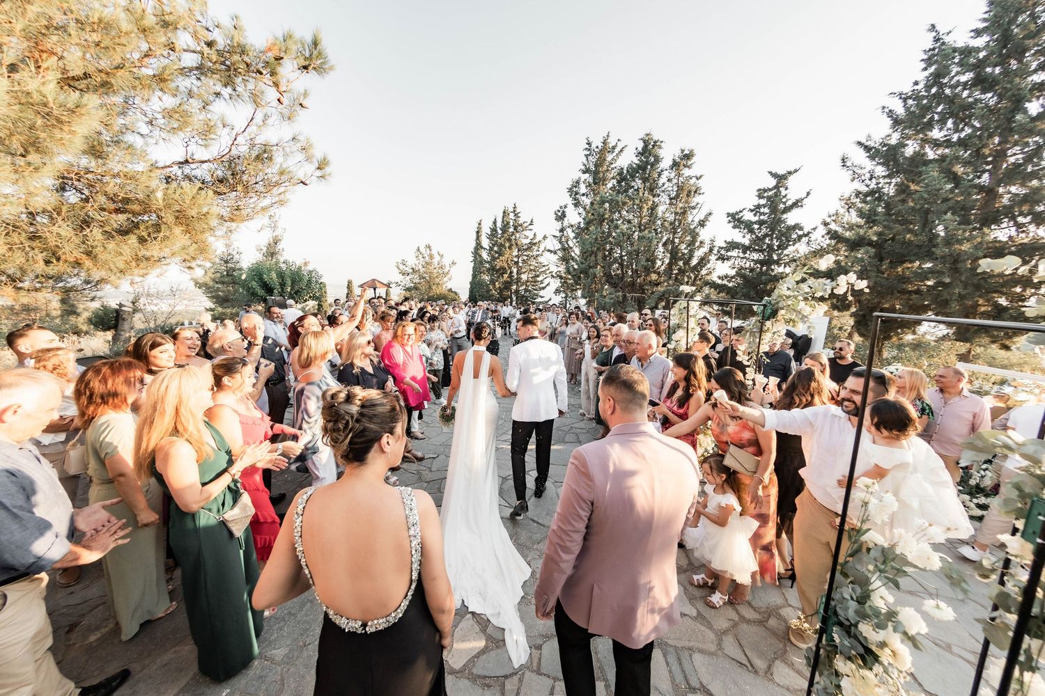 Wedding celebration with guests mingling outdoors against mountain backdrop at sunset.