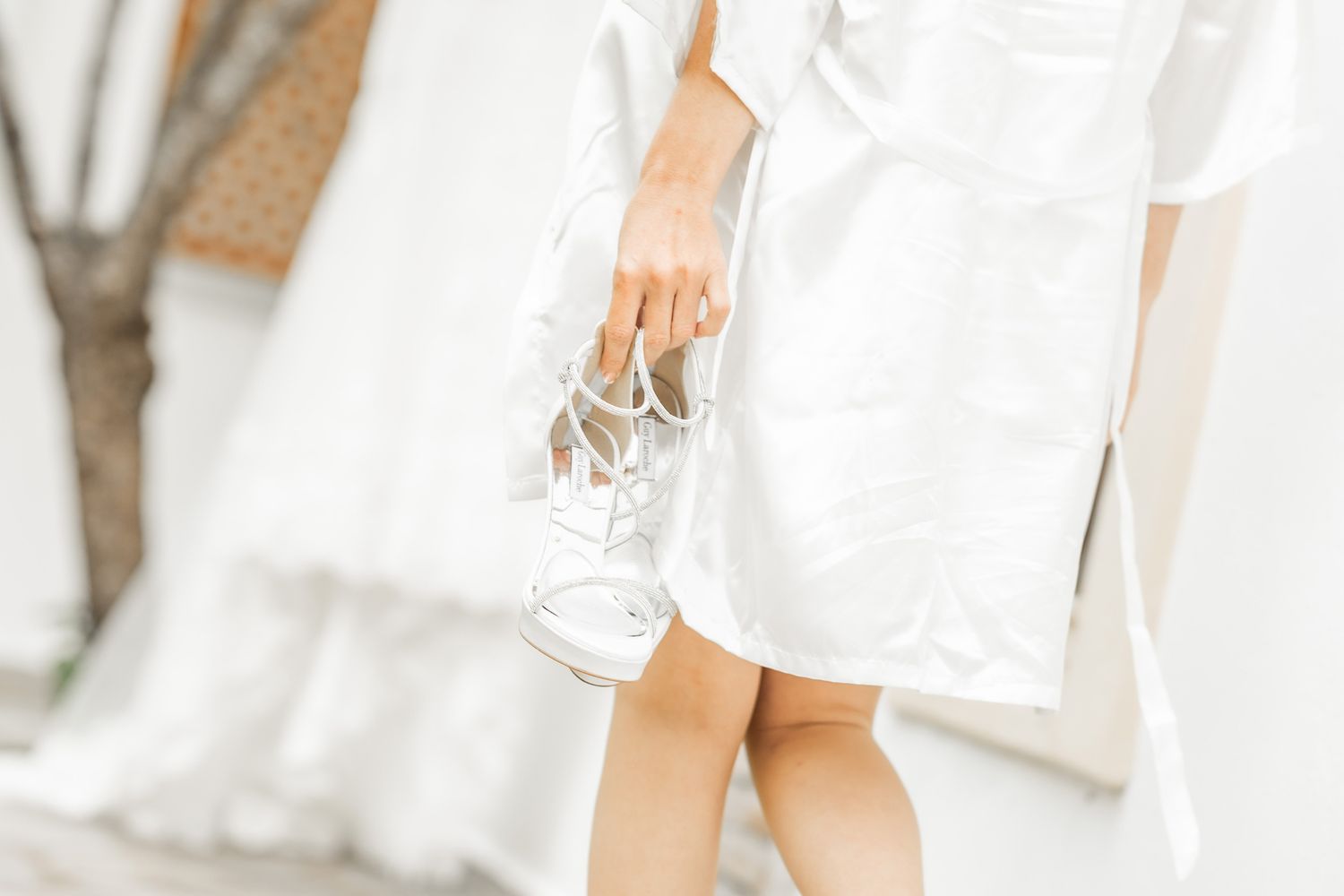 Wedding party members dressed in white and sage green dresses stand together in an elegant bridal preparation scene.