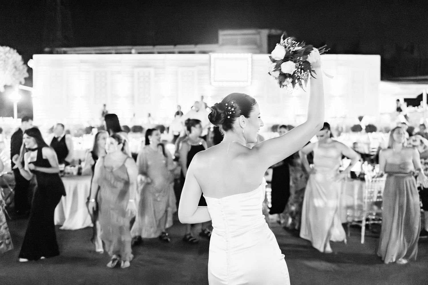 Wedding reception setup with elegant white decor and guest tables in a large venue.