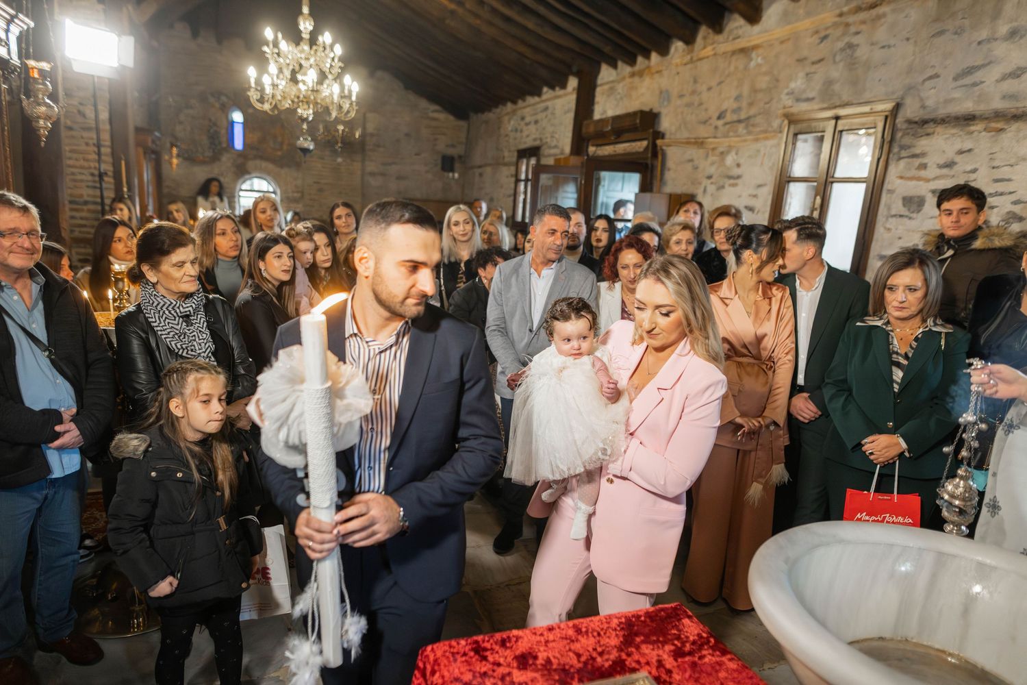 Wedding guests gather in a rustic stone-walled venue with chandelier lighting to celebrate the special occasion.