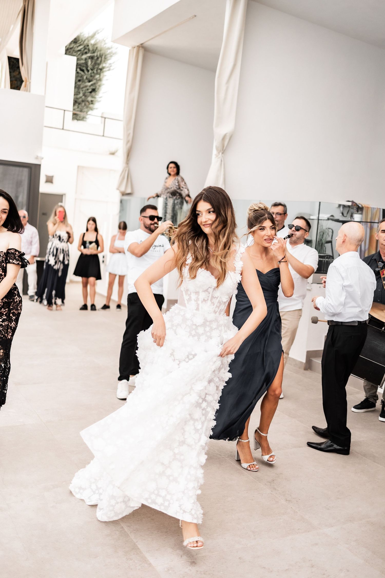 Wedding celebration with guests dancing in an elegant white indoor venue.