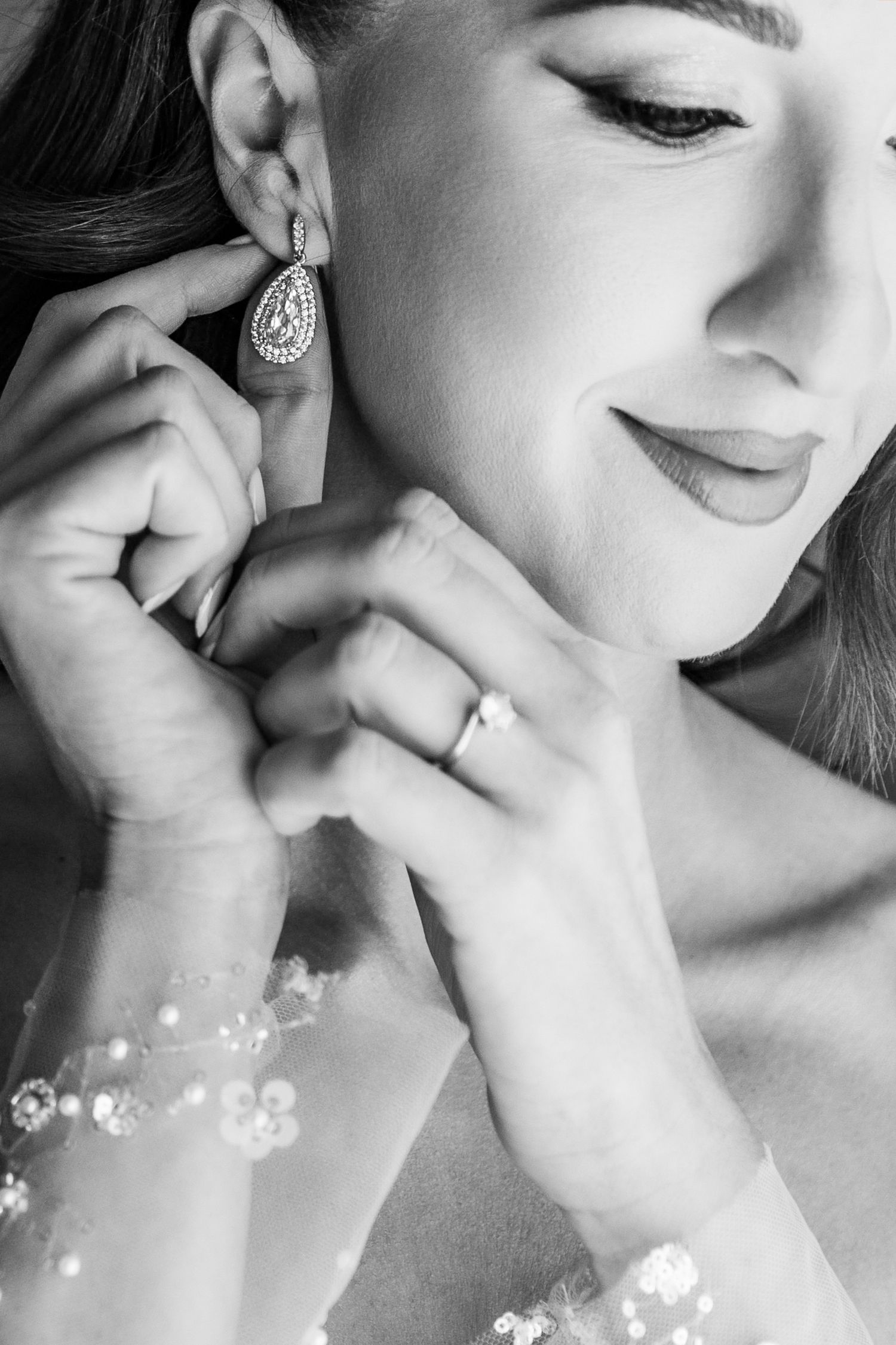 Close-up of teardrop earring and delicate bridal jewelry in black and white.