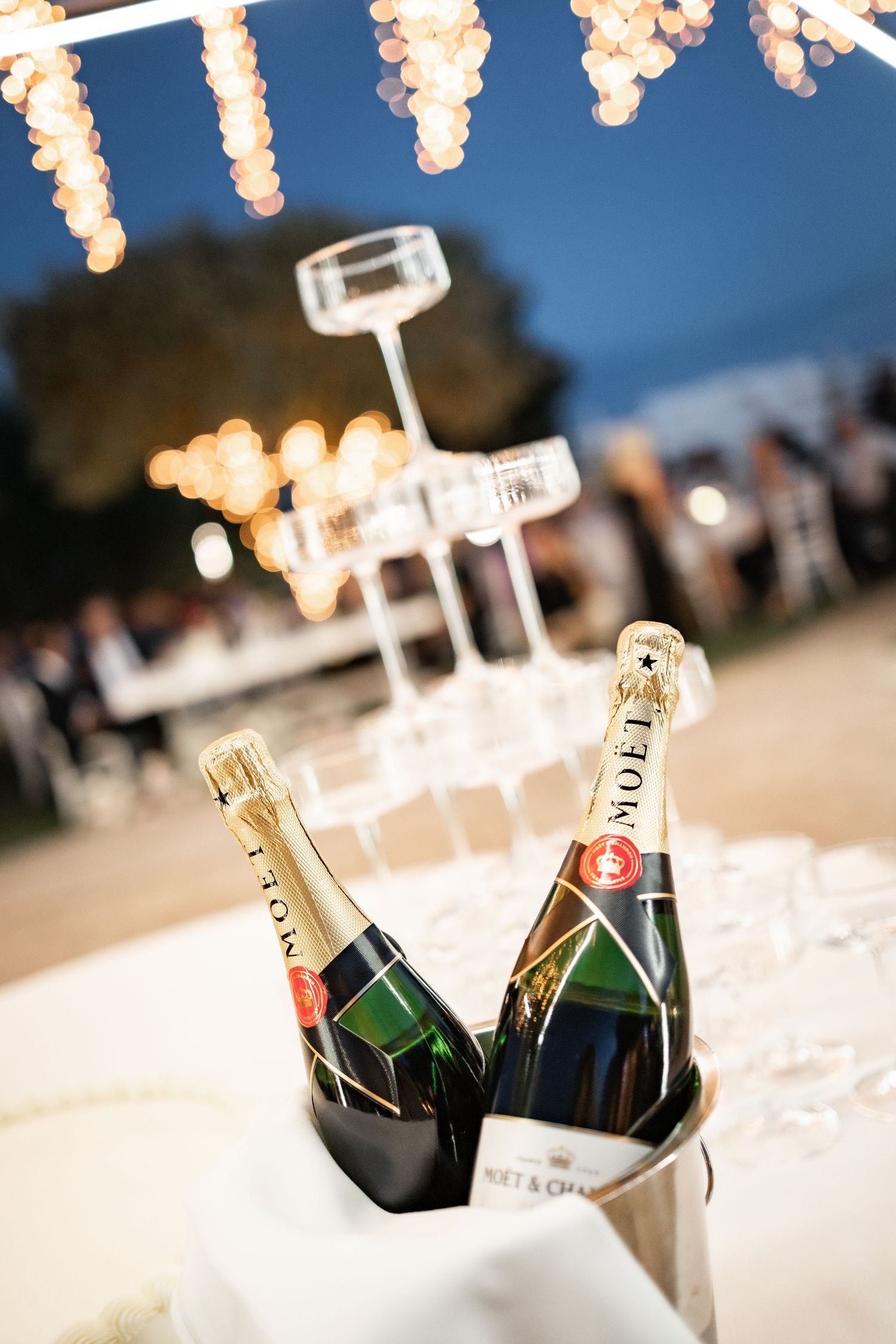 Two Moët & Chandon champagne bottles chilling in an ice bucket at an elegant outdoor evening celebration.
