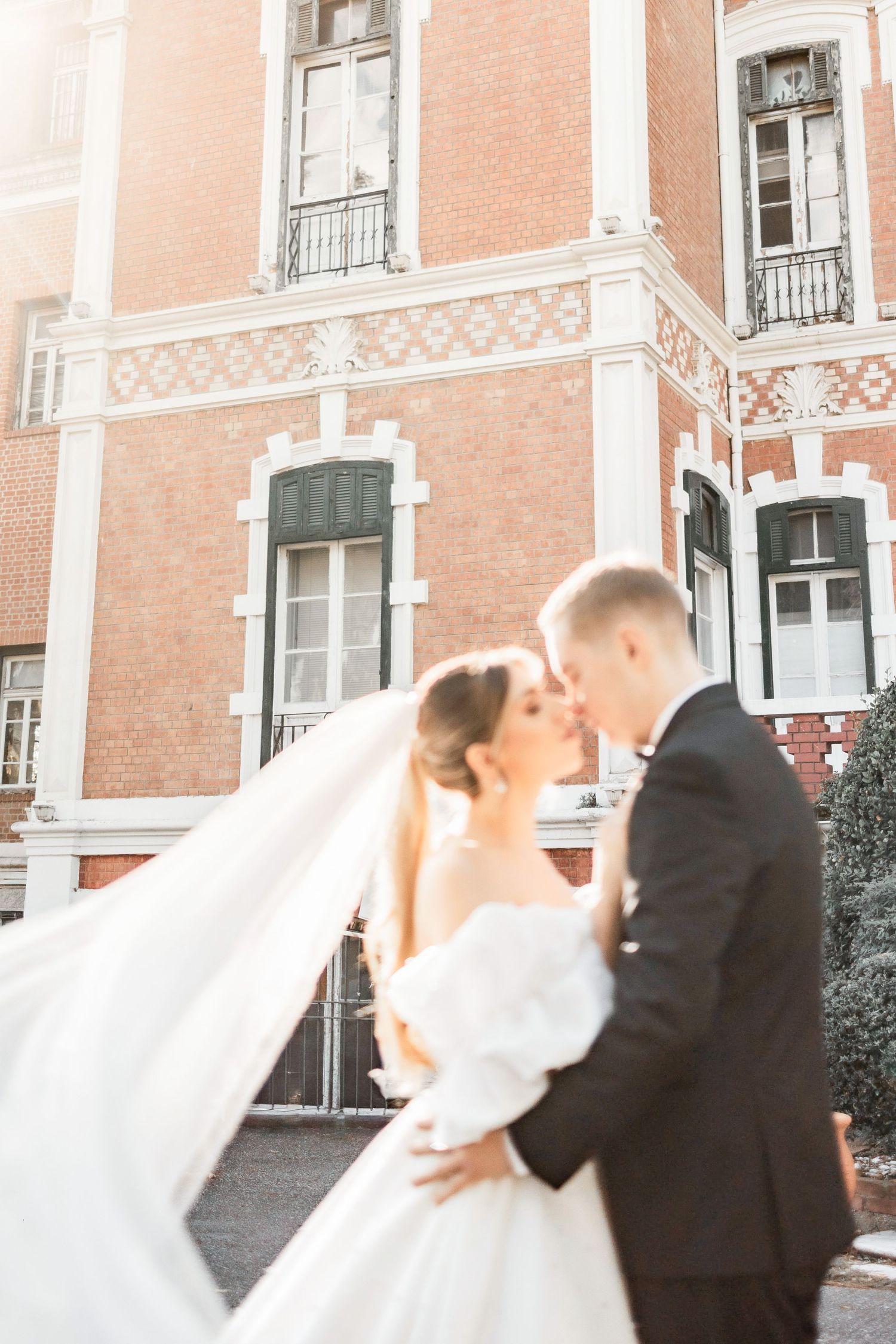 A tender wedding kiss captured against the backdrop of a beautiful vintage building.