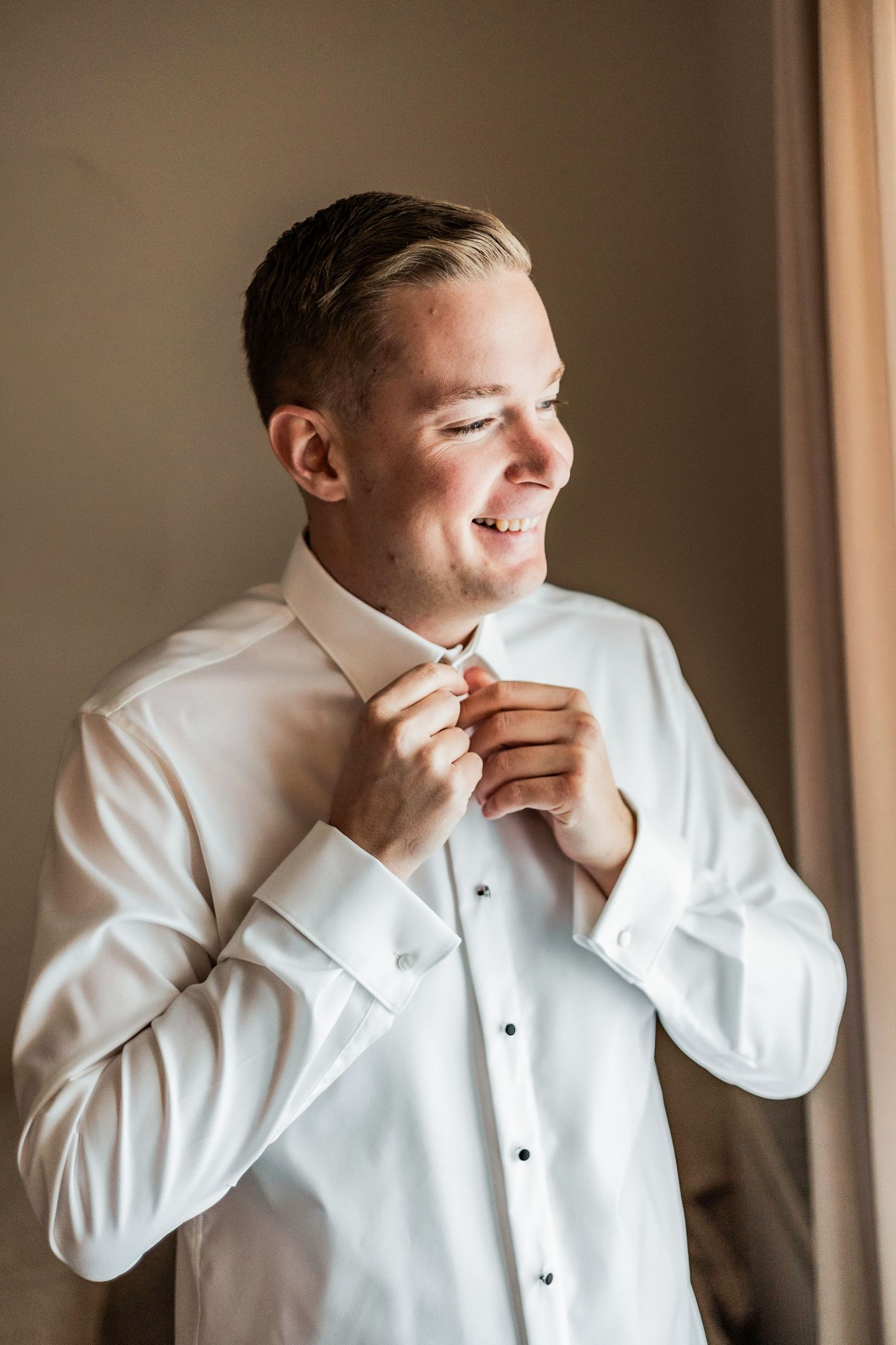 Getting ready sequence showing groom adjusting white bowtie before ceremony.