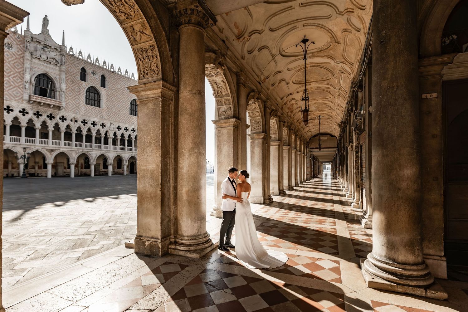 A couple embracing under the historic arches of Doge's Palace in Venice.