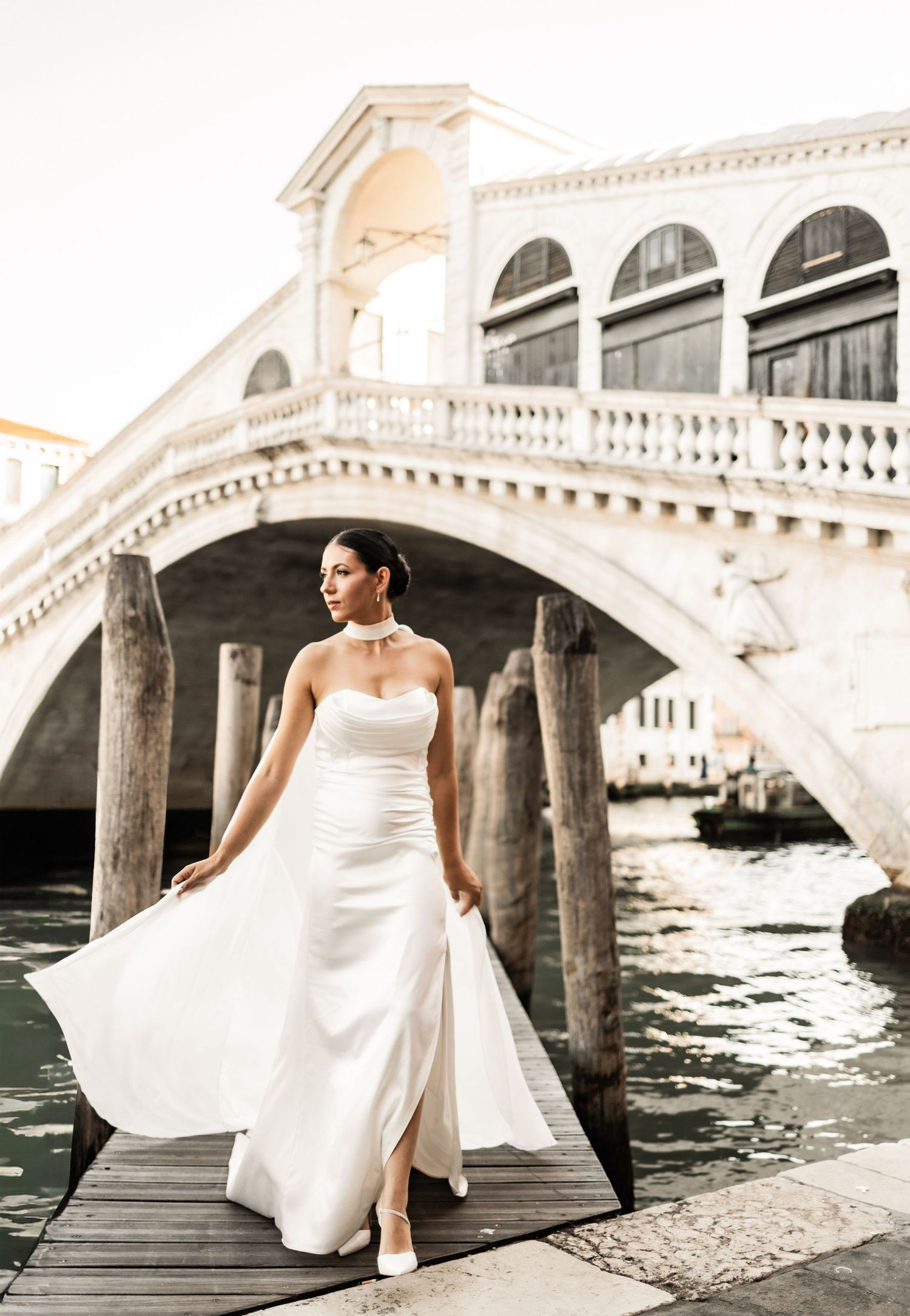 White dress billowing in the breeze near Venice's famous Rialto Bridge.