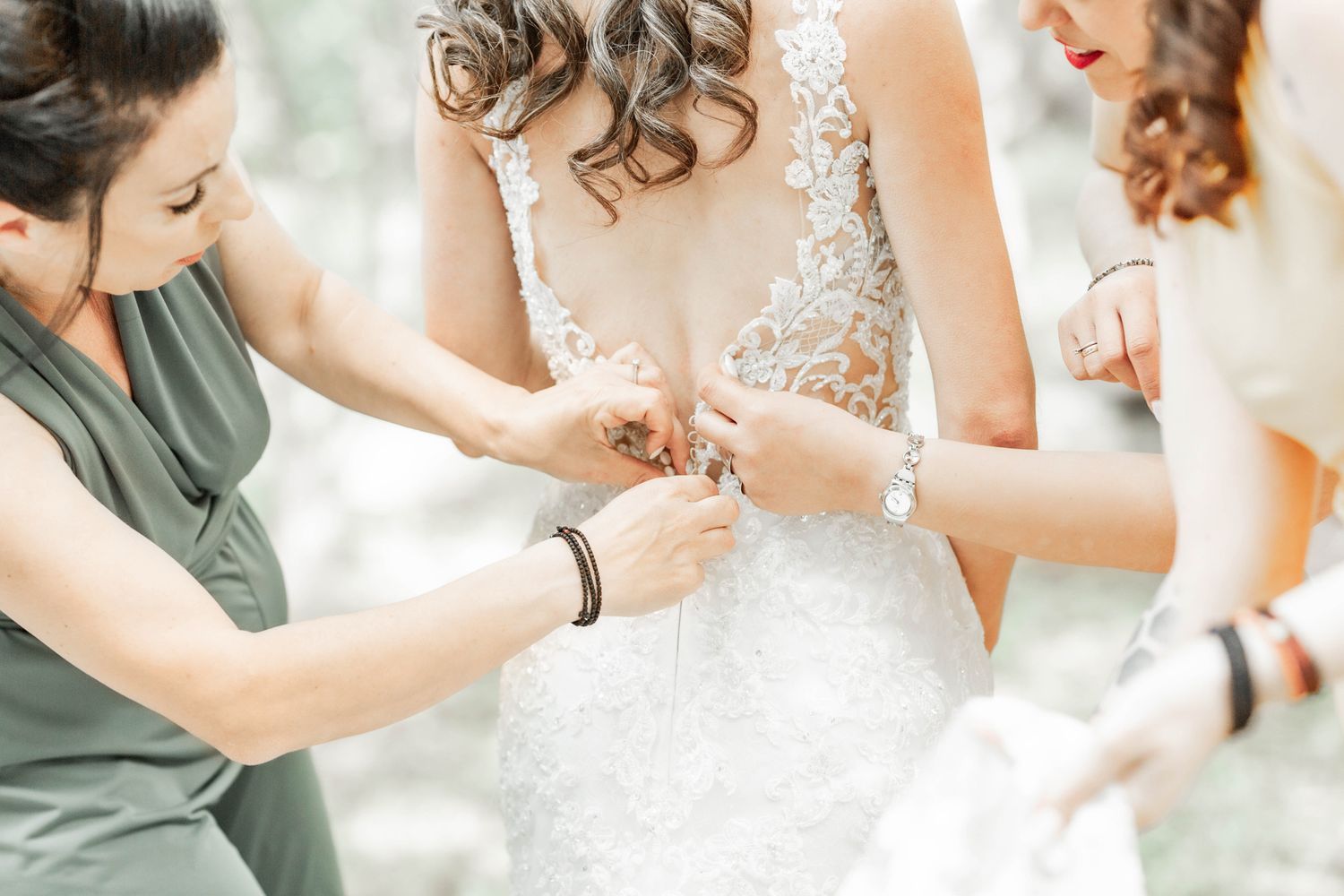 Delicate lace details of a wedding dress being adjusted during bridal preparations.