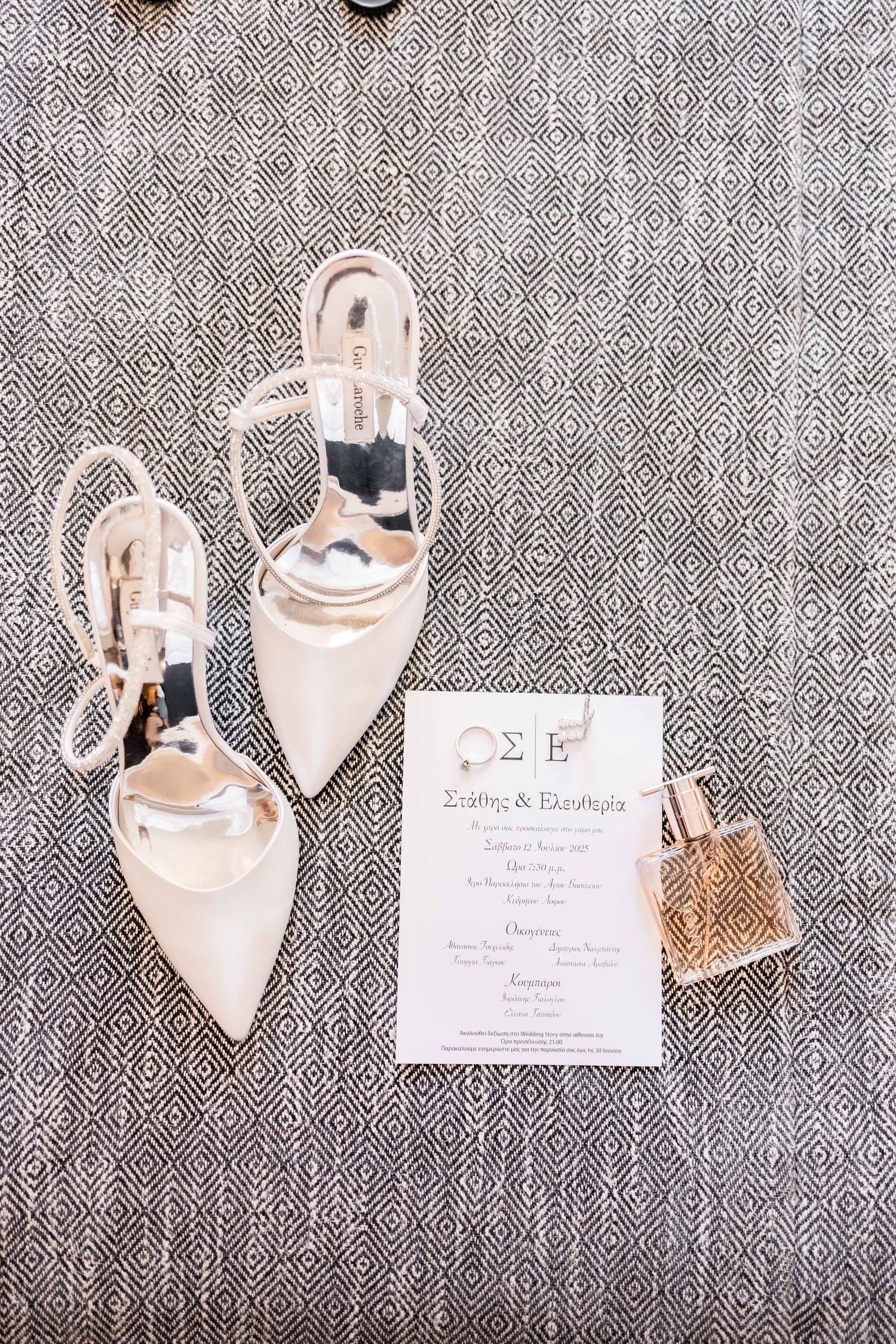 Elegant bridal shoes and wedding invitation displayed on textured gray fabric.
