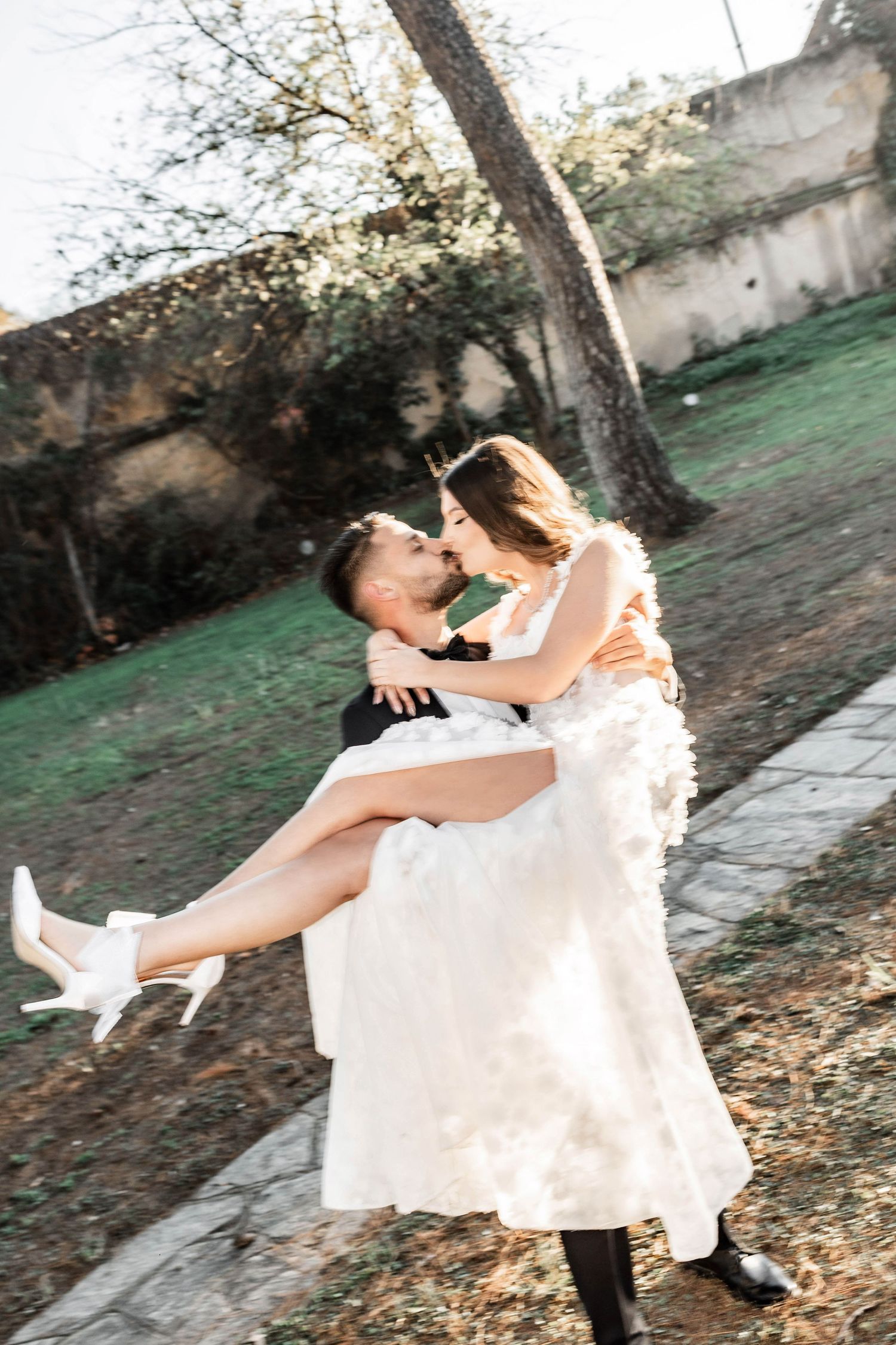 Romantic dance lift moment captured in an outdoor garden setting.