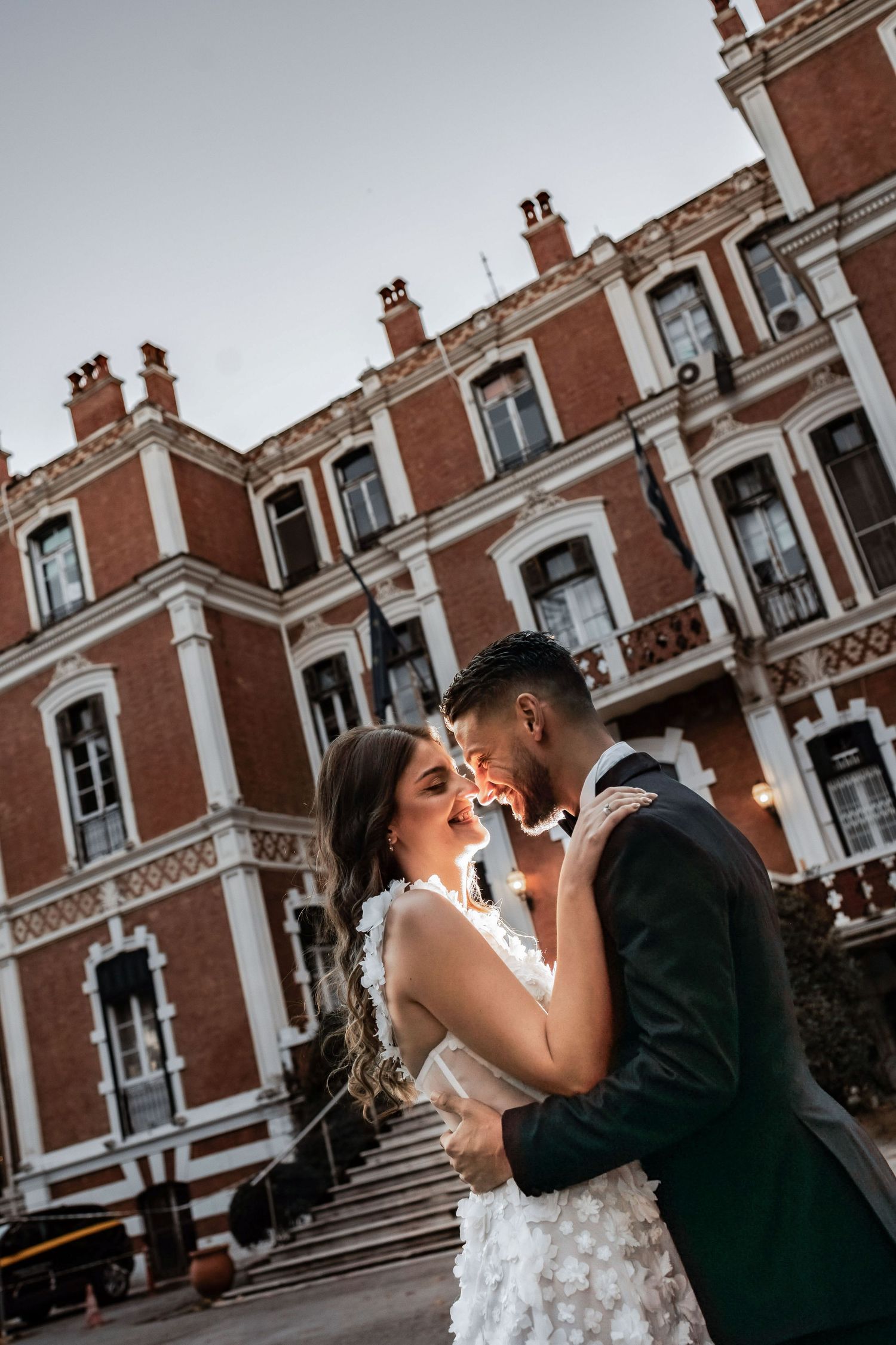 A romantic sunset wedding portrait against the backdrop of a historic brick mansion.