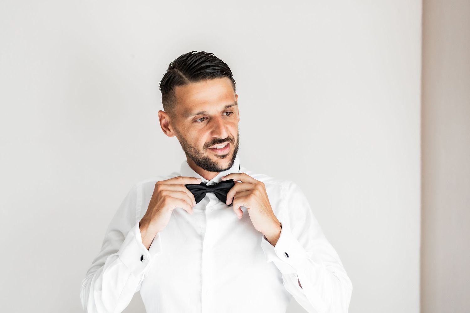 Wedding party member adjusting bow tie while getting ready.