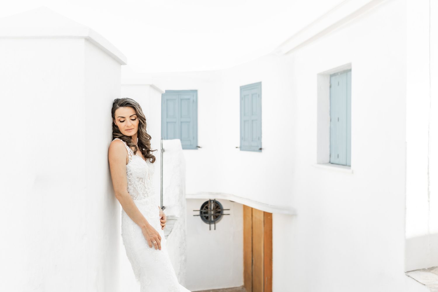 Elegant white wedding dress photographed against crisp white Mediterranean architecture.