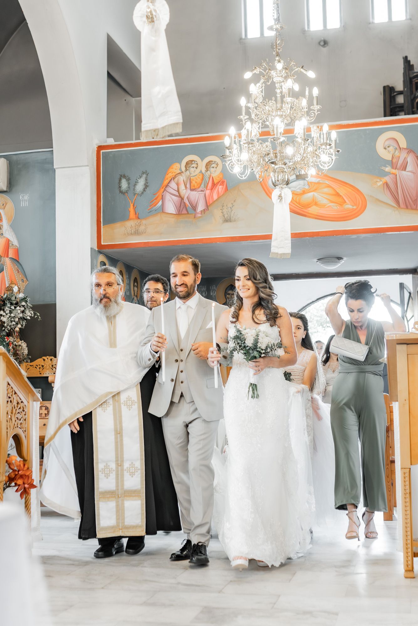 Wedding ceremony in an ornate church with chandeliers and religious iconography.