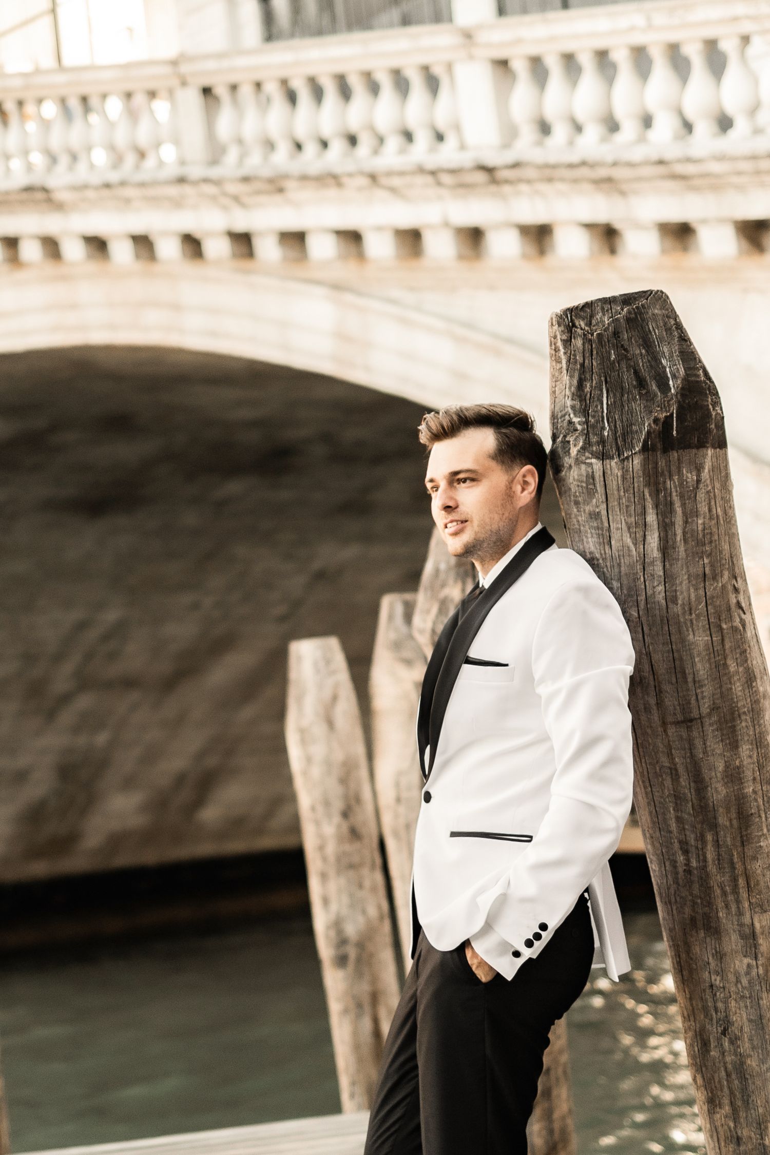 Classic formal attire against the backdrop of Venetian architecture and water.