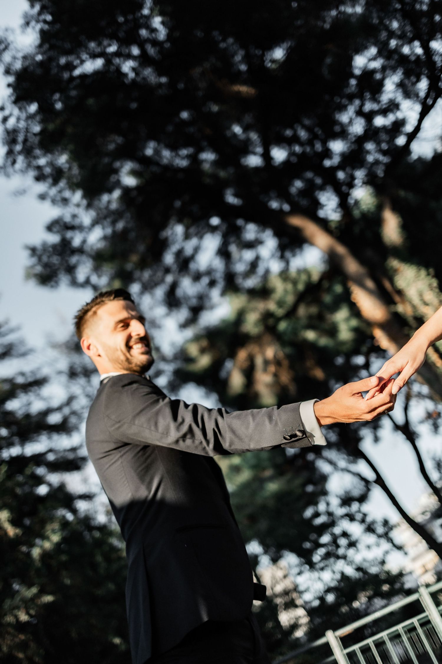 A joyful moment captured at an outdoor wedding ceremony with natural lighting and trees in the background.