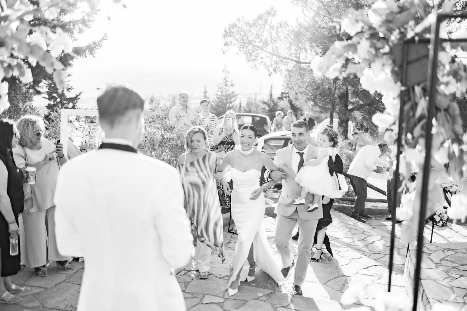 Wedding celebration captured in black and white with guests mingling outdoors.