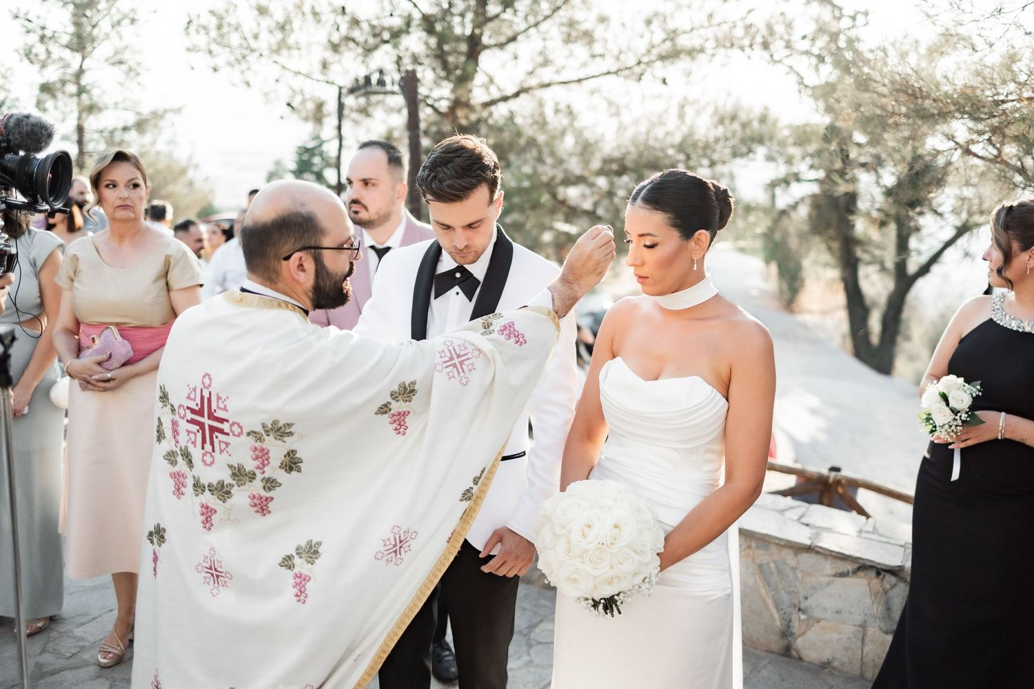 Wedding guests gather around to view decorative handkerchiefs at an outdoor celebration.