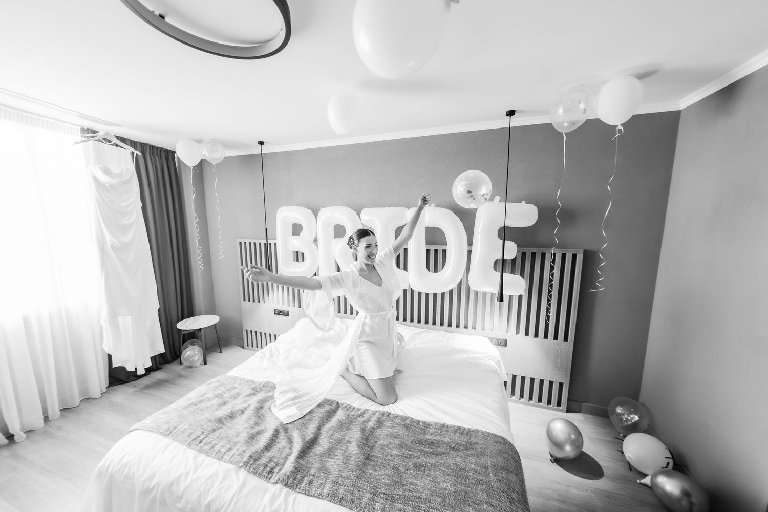 Modern hotel room decorated with BRIDE letters and balloons in black and white.