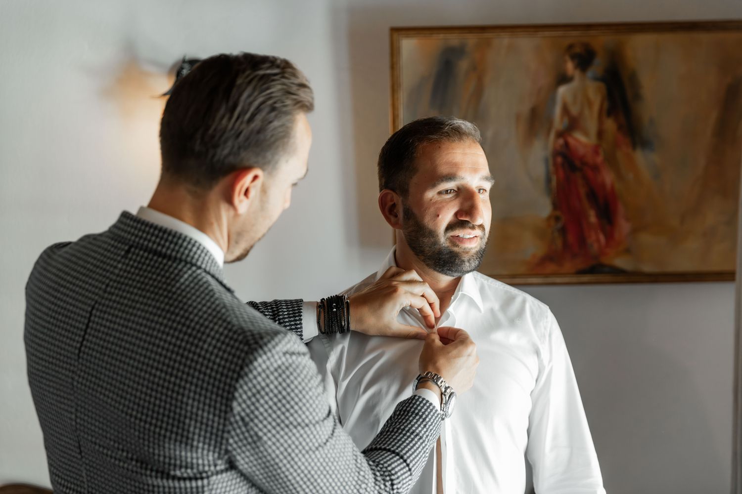 Wedding preparation scene showing final adjustments being made to formal attire.