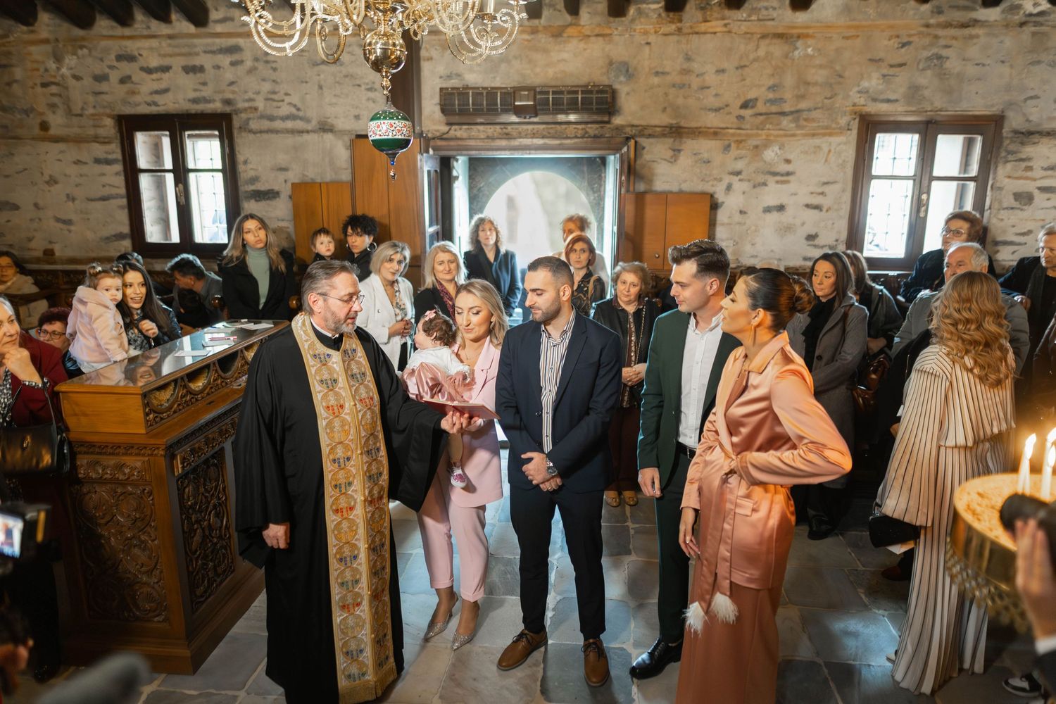 Wedding guests gather in a rustic stone-walled venue during a reception celebration.
