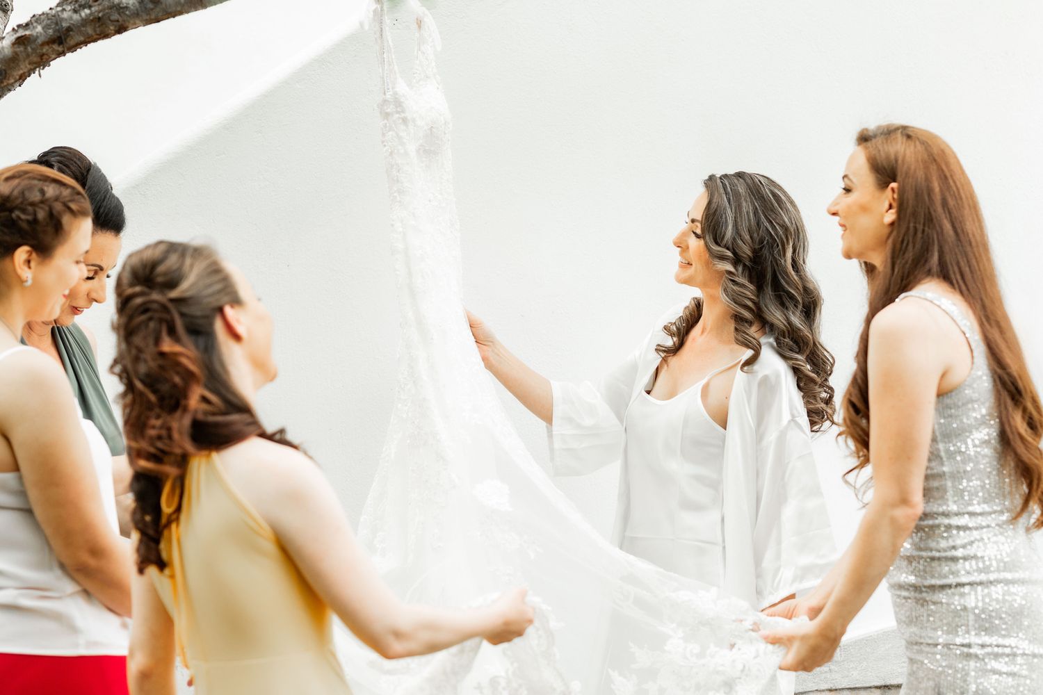 Wedding party members in formal attire gather together in an indoor setting.