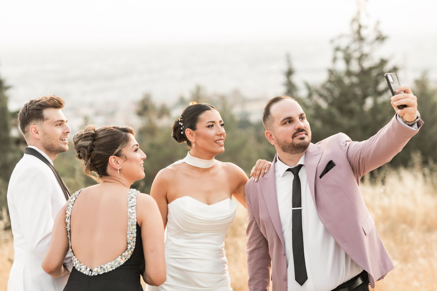 Wedding party poses together on scenic overlook with mountains in background.