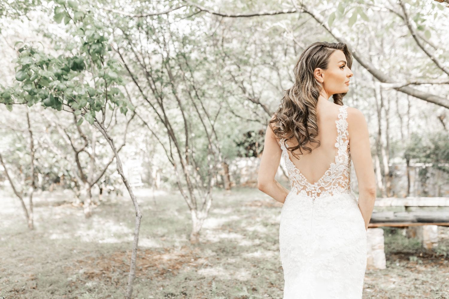 Wedding party poses along rustic stone wall in an outdoor garden setting.