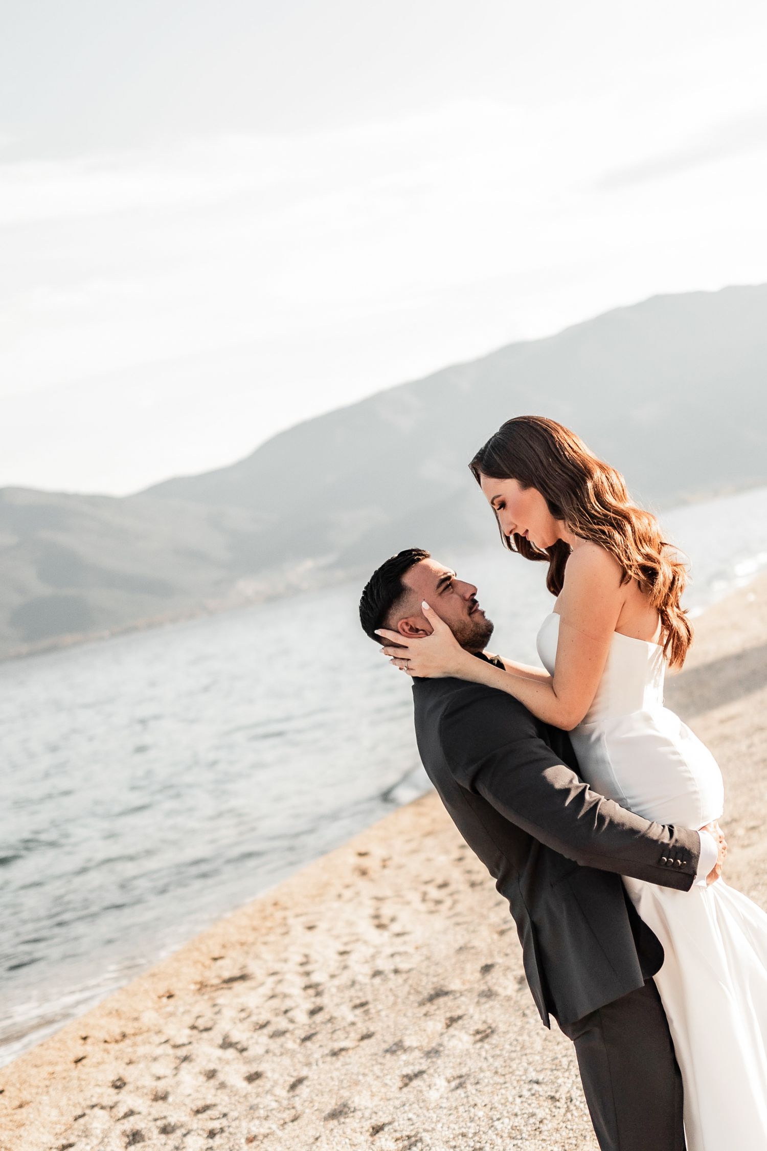 Newlyweds share an intimate moment on a scenic beach during sunset.