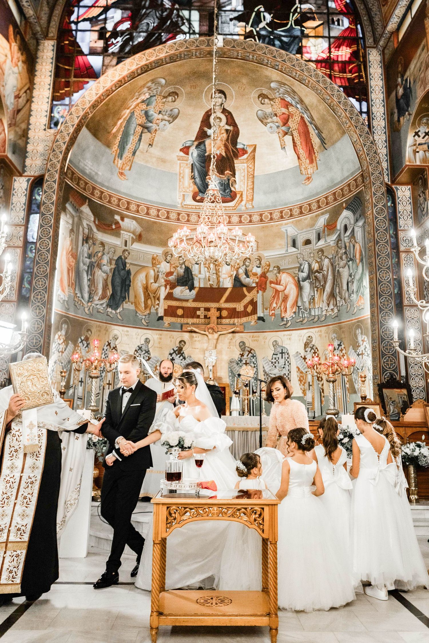 Ornate church interior with beautiful frescoes and chandeliers during a wedding ceremony.