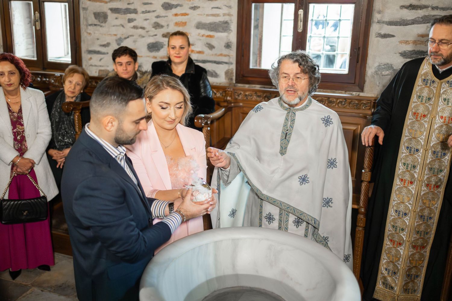 Wedding guests mingle and socialize during a reception in a rustic stone-walled venue with elegant decor.