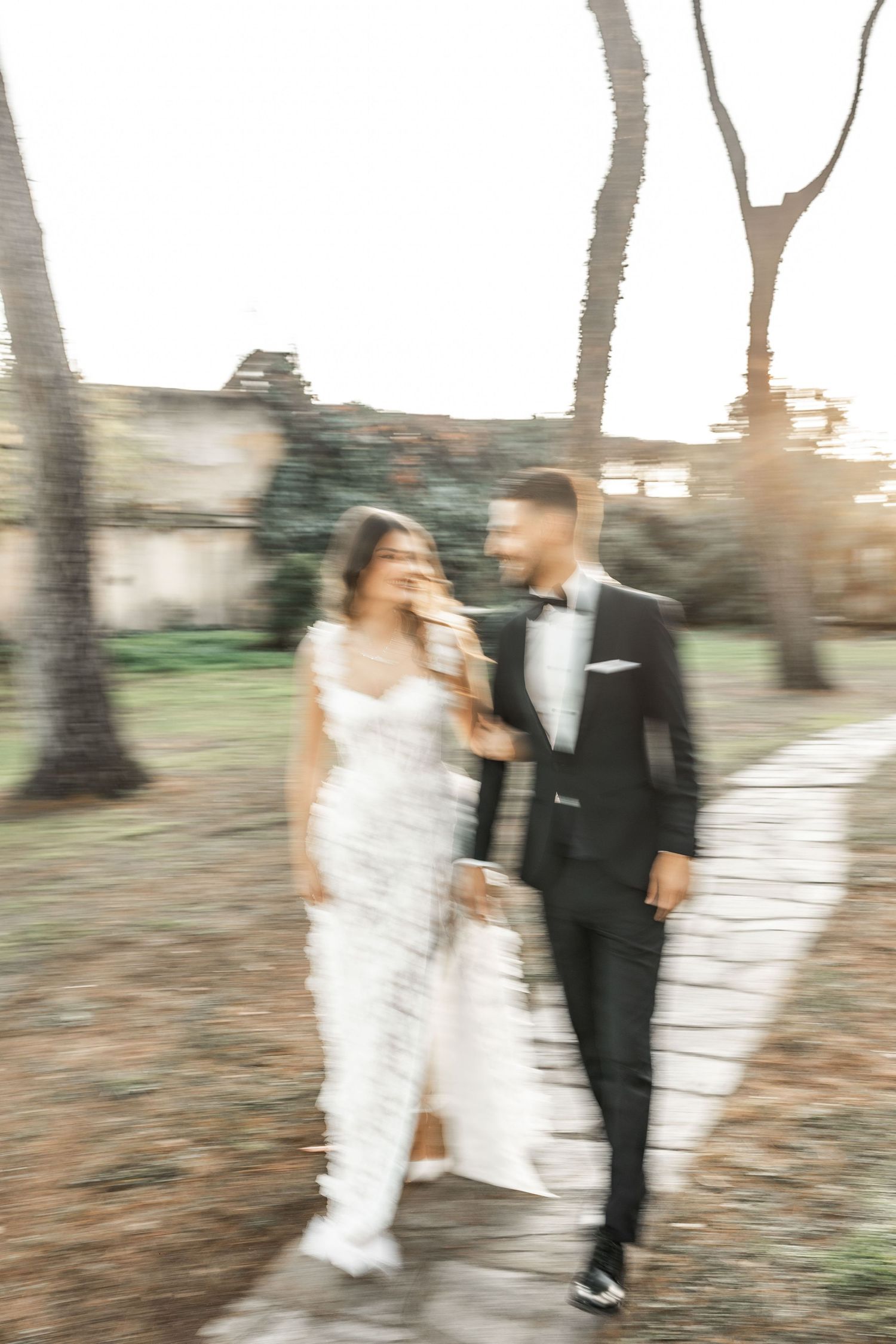Artistic motion blur shot of couple walking through a garden setting.