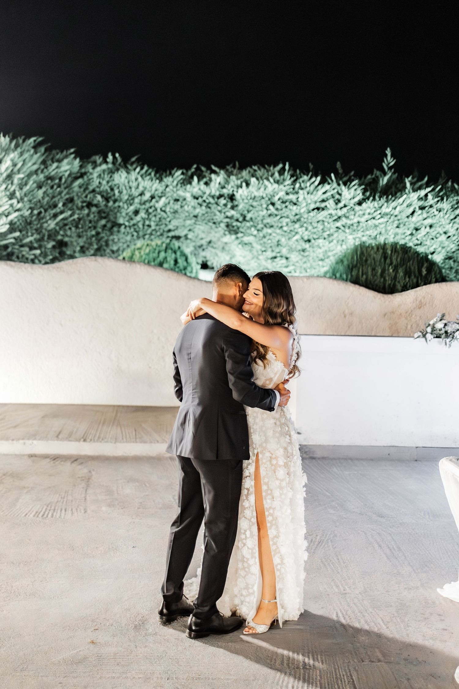 Couple shares an intimate slow dance moment on an outdoor patio at night.