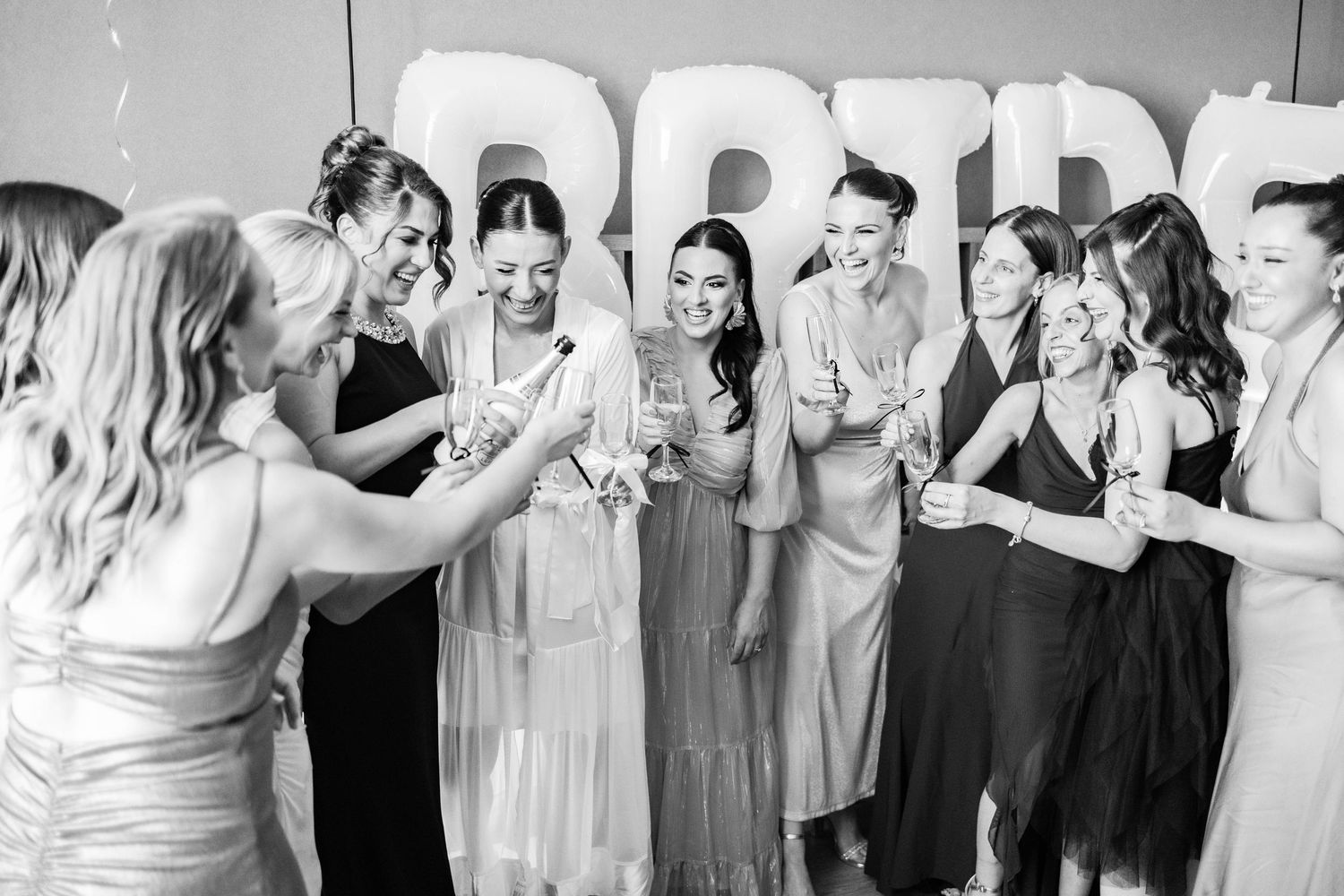 Wedding party celebrates in front of large BRIDE letters during pre-ceremony festivities.