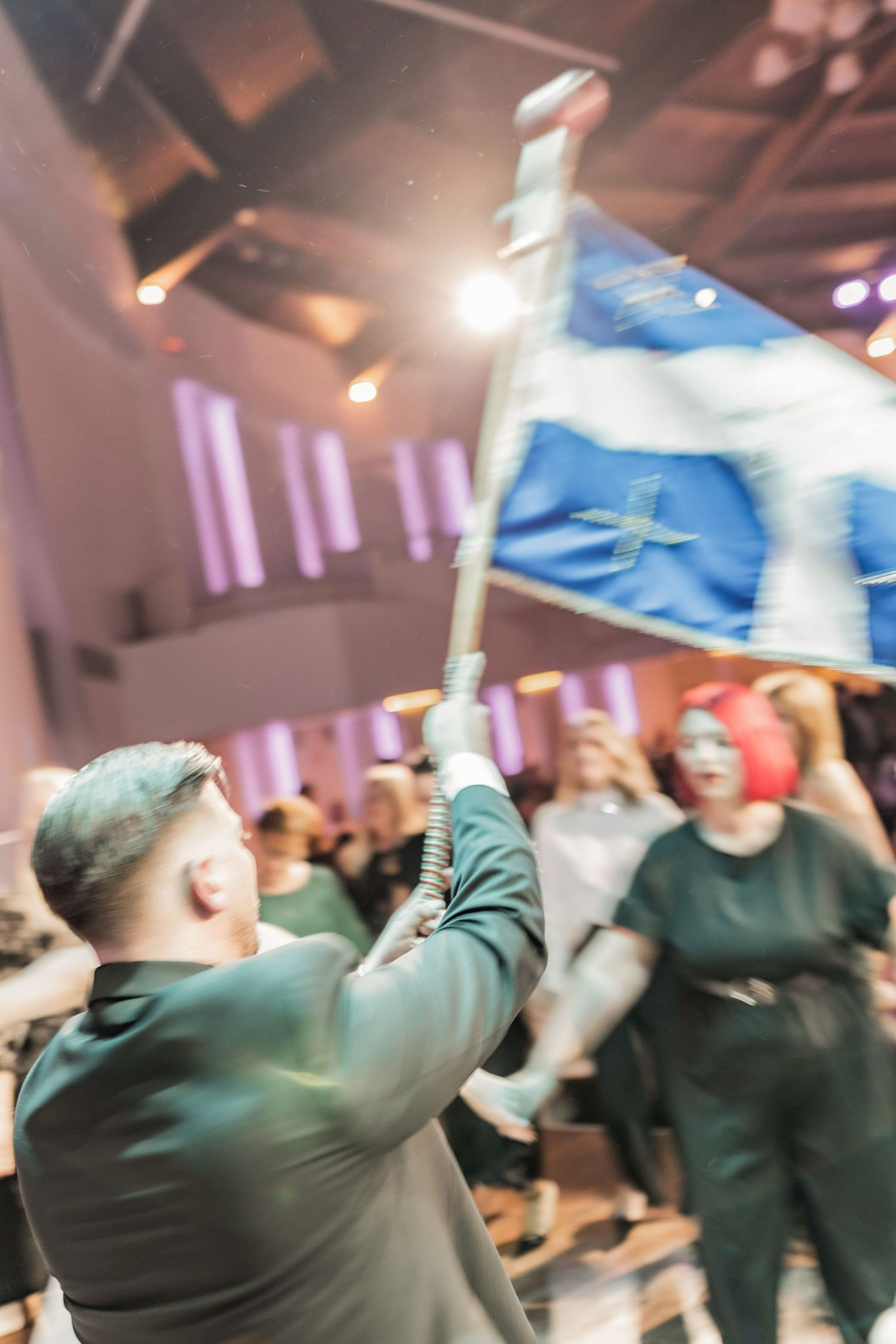 Energetic dance party scene with motion blur and purple lighting at a wedding reception.
