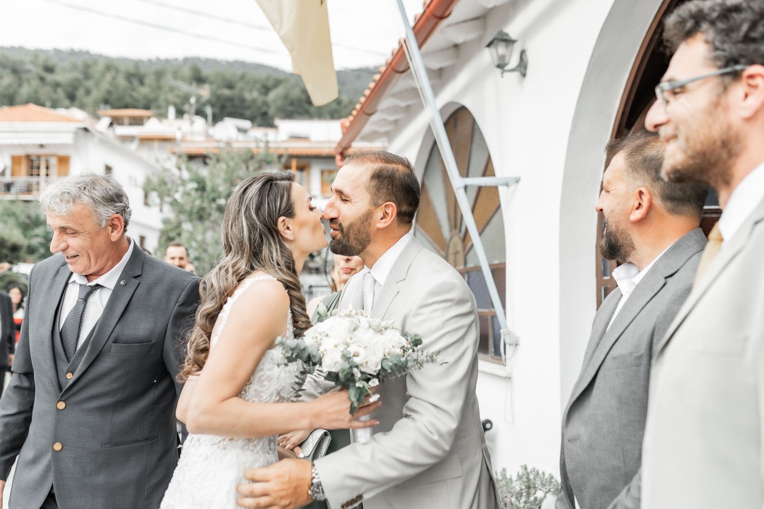 Wedding party members smile and laugh together in a candid outdoor moment.