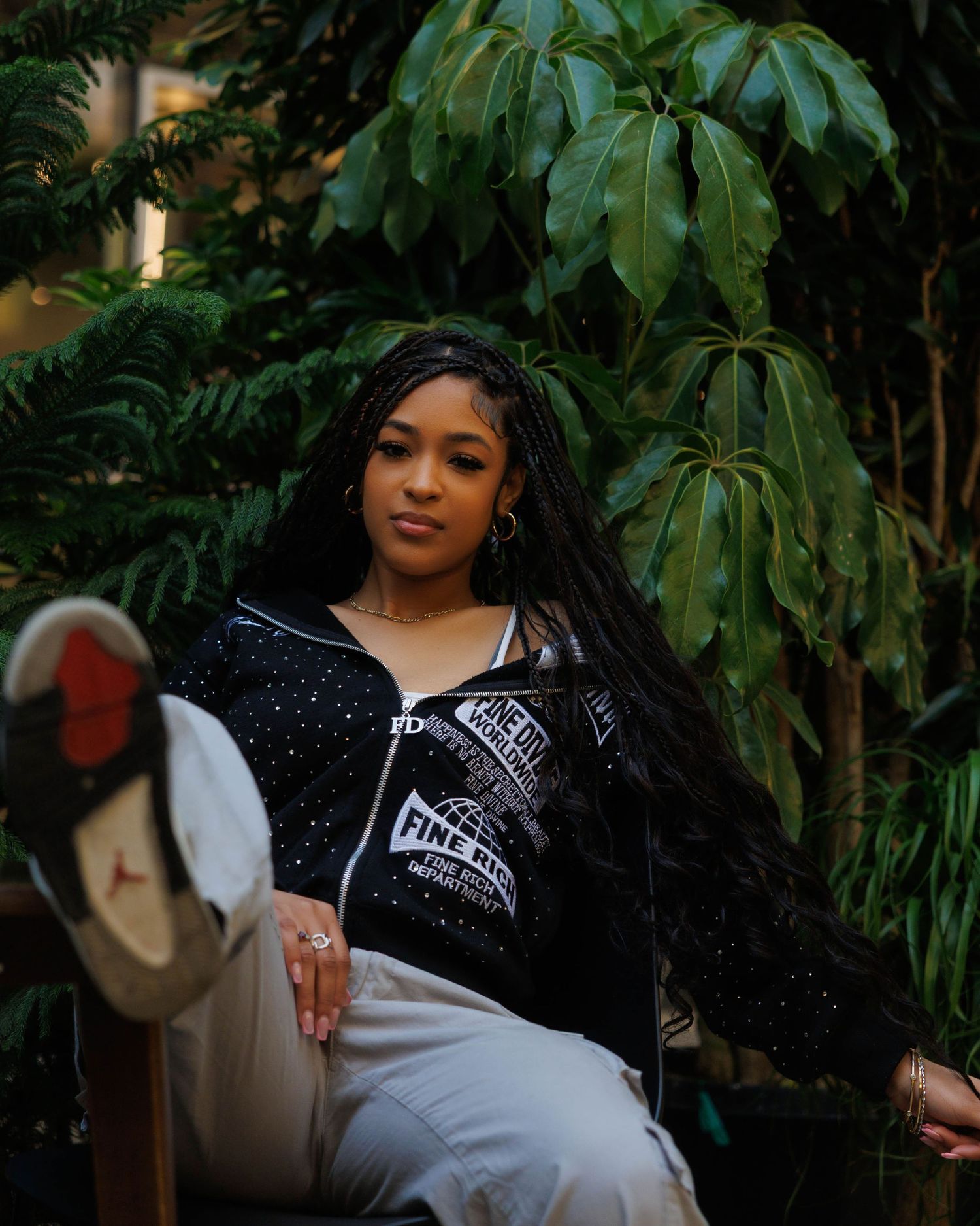 Fashion portrait in sparkly jacket against lush tropical foliage background.
